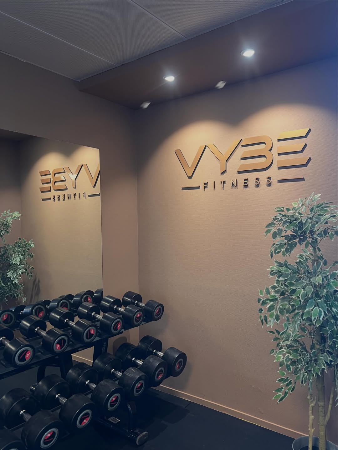 Treningslokaler til VYBE Fitness, veggen er dekorert med logoen. VYBE Fitness er ditt treningssenter på Forus