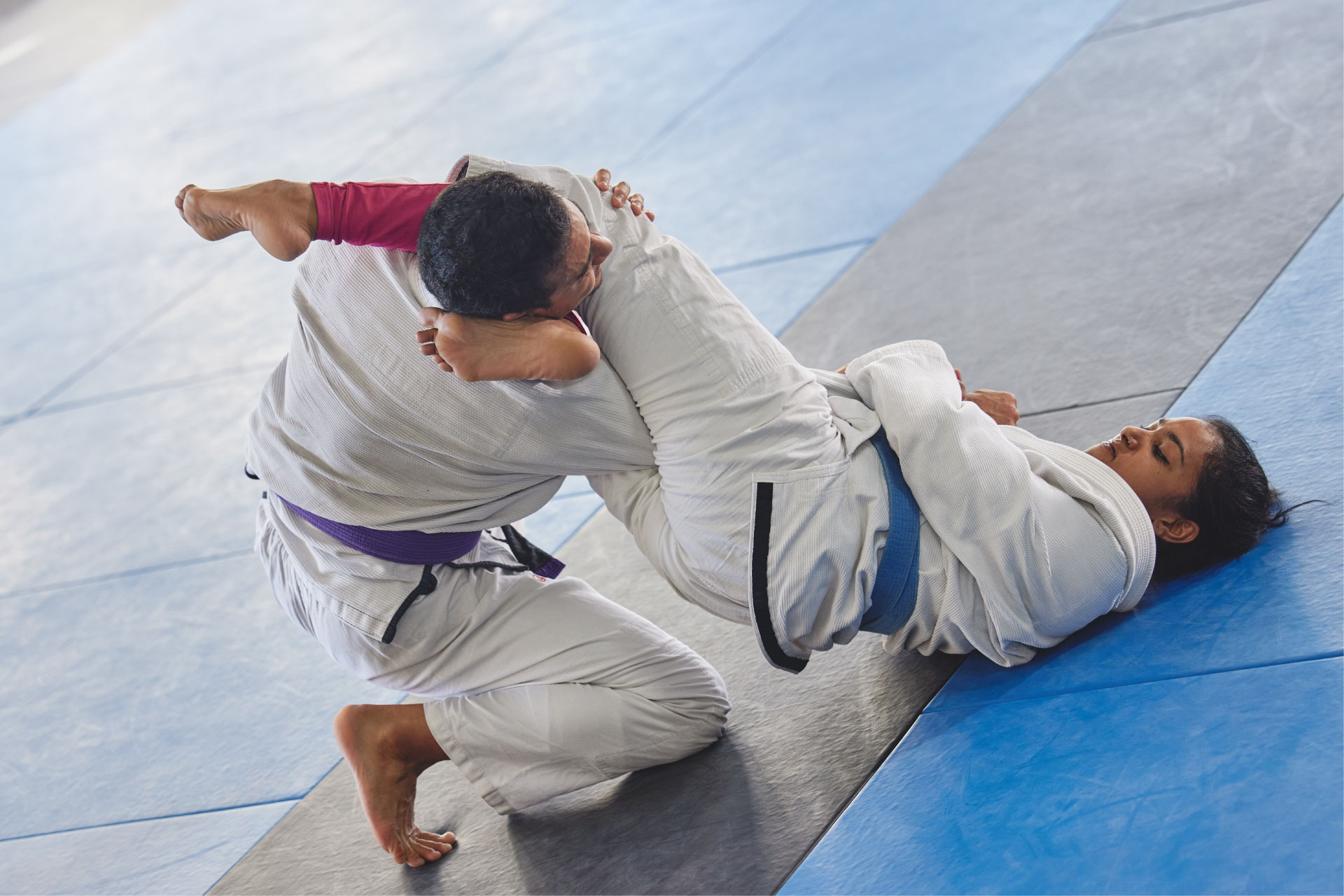 En mann underviser en dame i jiu-jitsu
